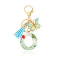 Floral resin keychain with red dried flowers, blue tassel and green butterfly pendant - Letter O