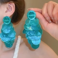 Primer plano de modelo luciendo pendientes grandes de lentejuelas turquesas brillantes - Estilo de Aguja de Plata de Disco Redondo Grande / Azul