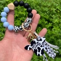 Detail of cow print beads and Mama cow head charm on leopard silicone keychain bracelet - Sky Blue/Cow Print