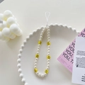 Detail of beaded phone strap with white pearls and yellow smiley face charms on a white tray - Pearl Smiley Face Bracelet