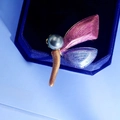 Makroaufnahme einer Libellenbrosche mit grauer Perle und Emaille-Flügeln in einer Schmuckschatulle - Rot Blau Weiß Farbverlauf Libelle-Muschelperle