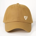 Detailed close-up of khaki cotton baseball cap featuring a white embroidered heart pattern - One Size / Turmeric