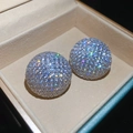 Vue macro des boucles d'oreilles sphériques pavées de cristaux dans un coffret - Aiguille d'argent - Paire d'argent