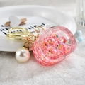 Detailed close-up of pink glitter liquid keychain with golden metal ring and pearl charm - Noctilucent TV Style / Red