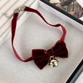 Detail eines burgunderfarbenen Samt-Chokers mit Schleife und goldener Glocke auf Display - Burgunderrot
