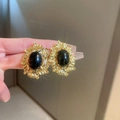 Close-up of gold metal floral earrings with black enamel worn on a finger to show detail - 58# Stud Earrings-Black Rhinestone