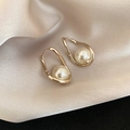 Close-up of gold irregular loop earrings with white pearls on champagne silk fabric - Chocolate Gold