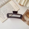 Detail of matte dark coffee rectangular hair claw clip on an open book in cozy light - Matte Large Square Dark Coffee