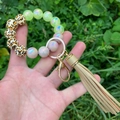 Close-up of leopard print and glowing beads on a keychain bracelet with golden tassels - Brown Leopard