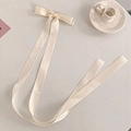 Elegant large cream ribbon bow hair clip with long flowing tails on white table - Beige Streamer Bow Hair Clip