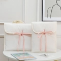 Quilted off-white 13-inch laptop sleeve with sweet pink ribbon bow in a cozy home setting - 11" / Off White