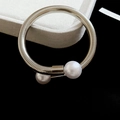 Primer plano detallado de un brazalete plateado con dos perlas blancas en caja de joyas - Brazalete - Plata