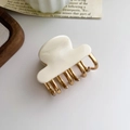 Detail of cream acetate and gold metal claw clip on a minimalist aesthetic background - Cream White