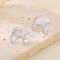 Minimalist ginkgo leaf earrings in silver finish on a textured beige stone background - Steel Color (KE114634-KFC)