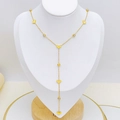 Detail of golden Y-shaped tassel necklace with heart and crystal charms on display - Heart Style