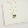 Golden fish pendant necklace with blue enamel details on white textured block - Blue