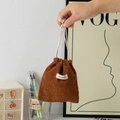 Detail of brown corduroy drawstring bag with Gianmeilin label held by model - Brown