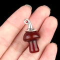 Dark red agate mushroom pendant with silver loop held by fingers for size display - Gun Black Cap / Red Agate