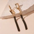 Detail of long geometric gold earrings with black metal tassel chains on stone - Black Asymmetric Tassel (Silver Pin)