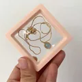 Pink PE film jewelry storage box holding a gold chain necklace with blue gemstone - Light Pink / Round Base (1pc)