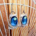 Vintage silver oval moonstone drop earrings with blue-green stones on a dark wood background - Blue
