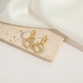 Close-up of golden round drop earrings featuring micro-set white zircon on stone - Pave Hoop Style