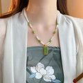 Collana lunga con perle bianche e perline di giada verde elegante su un abito bianco - Perline Bianche e Verdi Con Pendente Abaco Verde