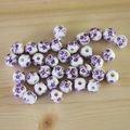 Close-up of ceramic white beads with purple floral patterns on a wooden surface - No.34-Purple Floral