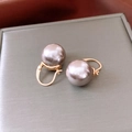 Primer plano de elegantes perlas de vidrio gris púrpura en aros dorados en un joyero - Poste de plata - Dorado - Gris