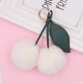 Sweet cherry plush keychain with two white fur balls and golden spring ring on pink surface - Spring Ring / Off-white