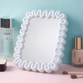 Miroir de maquillage blanc à bord ondulé avec support pliable sur fond décoratif coloré - Bleu Clair Carré