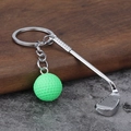 Detail van golfclub sleutelhanger met groene bal op steen- en houtachtergrond - Groen