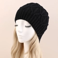 Close-up of black cable-knit beanie with textured diamond pattern on display model - One Size / Black
