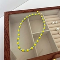 Close-up of handmade beaded necklace with yellow and green-white stripes in a jewelry box - Yellow-Green Beaded Pearl Necklace