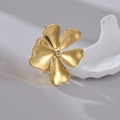 Makro-Detail von goldenem Blumenring mit zentralem Zirkon auf weißem Keramikhintergrund - Übertriebener Großer Blumenstil