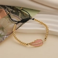 Fashionable gold beaded bracelet with a pink enamel leaf pendant and adjustable black cord - Nude Pink