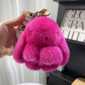 Rose red rex rabbit fur bunny charm with golden clasp held against a soft background - 10cm Bunny / Rose Red