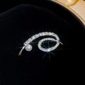 Dettaglio macro di una spilla a spirale argentata con zirconi lucenti e una perla bianca - Argento