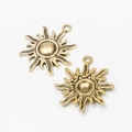 Detail of two vintage bronze sun-shaped metal alloy pendants with intricate wavy ray patterns - Antique Gold