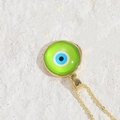 Golden chain necklace with green resin evil eye round pendant on a stone background - Green