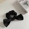 Chouchou élégant en satin noir avec un grand nœud sur un fond minimaliste chic - Chouchou papillon noir