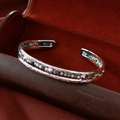 Macro shot of silver metal bangle with turquoise beads and heart charms on leather background - Silver