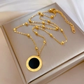 Dettaglio collana in titanio dorato con ciondolo romano nero su sfondo morbido - Oro
