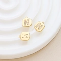 Makro-Detail von vergoldeten quadratischen Anhängern mit Zirkonia-Inlay und den Buchstaben N und Z - Buchstabe N