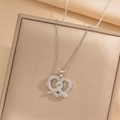 Collar de corazón pretzel plateado con diamantes de imitación en un joyero color beige - Forma de Corazón Pretzel / Color Acero (424)