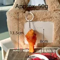 Realistischer PVC Brathähnchen-Schlüsselanhänger an einer beigen Plüschtasche - Orleans Hähnchenkeule
