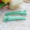 Pair of mint green seamless wave and straight metal hair clips on white lace background - Emerald