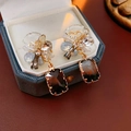 Detail view of flower-shaped diamond earrings with dark rectangular pendants in a jewelry box - Dark Brown Flower Cluster Geometric Style
