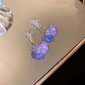 Macro di orecchini a cuore viola con pavé di diamanti scintillanti su superficie a specchio - Stile Cuore / Viola