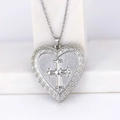 Silver heart locket necklace with embossed cross and Greek key pattern on white stand - Cross Heart/Steel